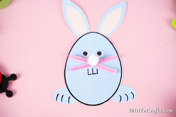 Egg shaped Easter bunny card on pink surface
