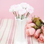 Paper flowers in white vase on pink table