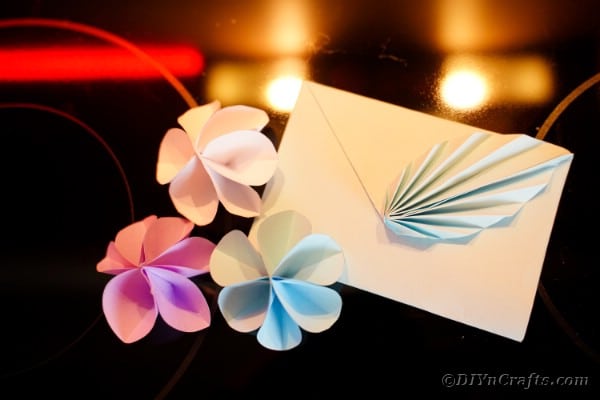 Origami envelope with flowers on table