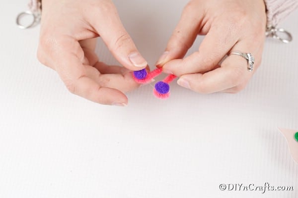 Adding pom poms to pipe cleaners