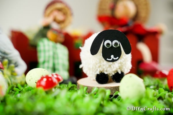 Pom pom sheep on circle of wood with red behind