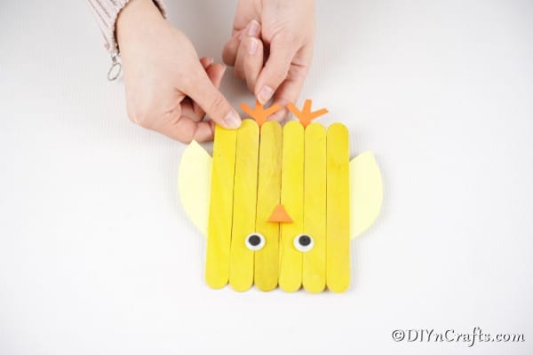 Gluing beak and feet to popsicle stick chick