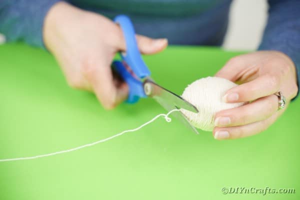 Cutting yarn and gluing in place on egg