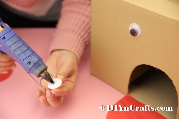 Gluing googly eyes onto cardboard box