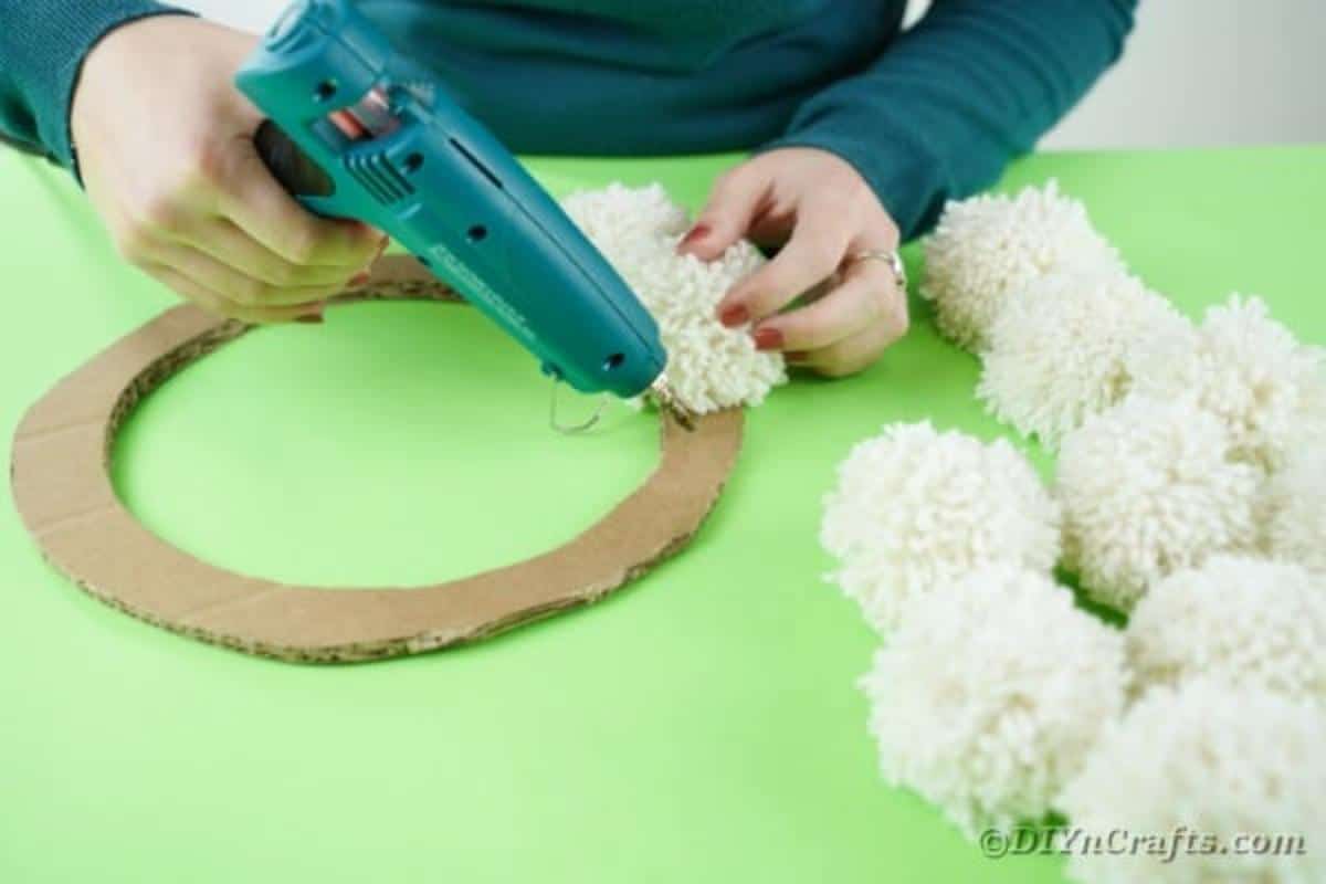 Glueing the pom poms to the wreath frame