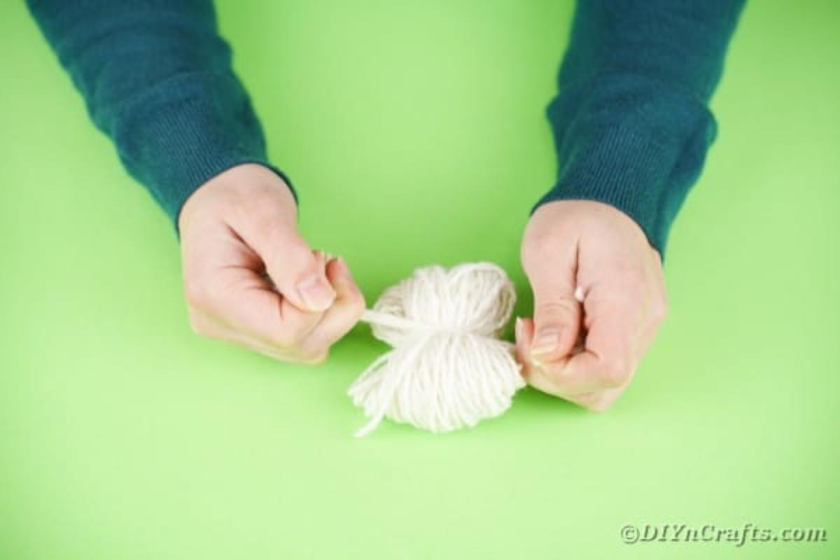 Tying another piece of yarn around the middle of yarn
