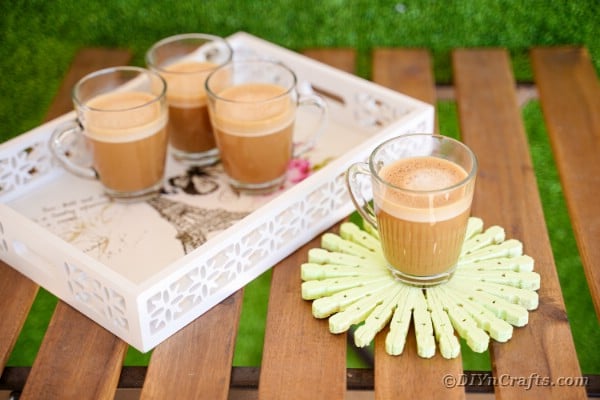 Serving tray on wooden bench with coffee cups and coaster