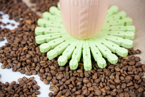 Green clothespin coaster surrounded by coffee beans
