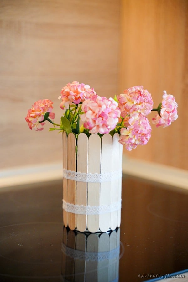 Craft stick can with pink flowers on wood table