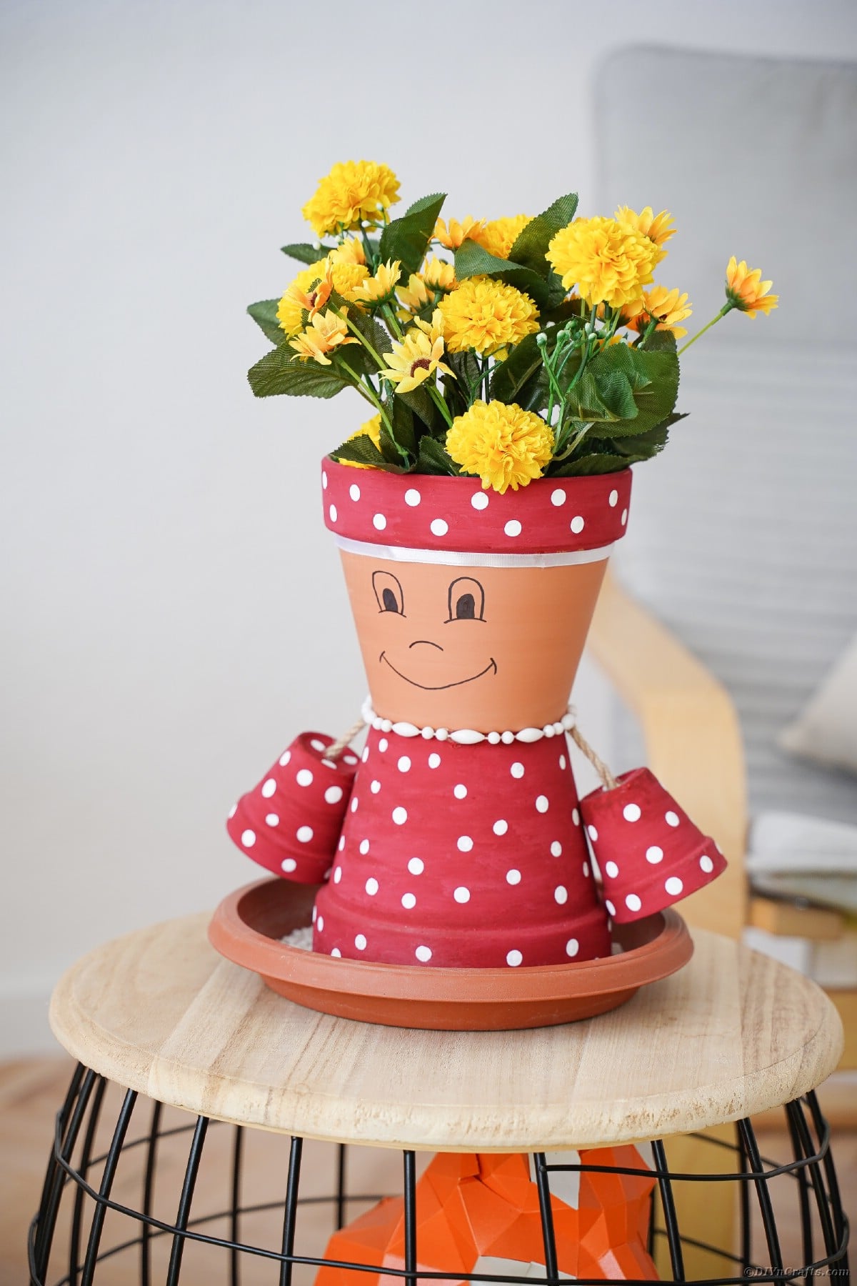 Pink and white polka dot clay pot person on stool