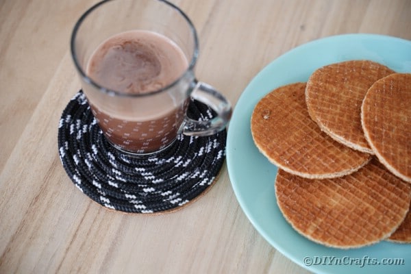 Coffee cup on coaster by plate of waffles