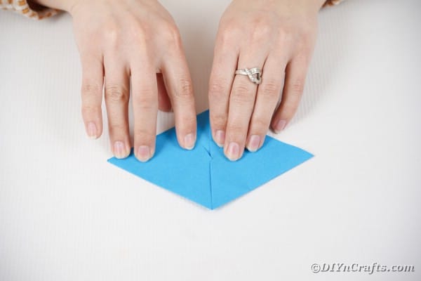 Hands folding blue paper