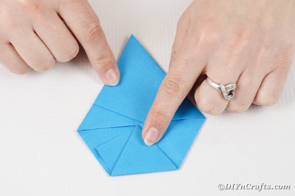 Hands folding blue paper