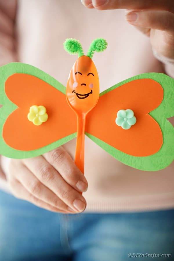Woman holding orange and green butterfly