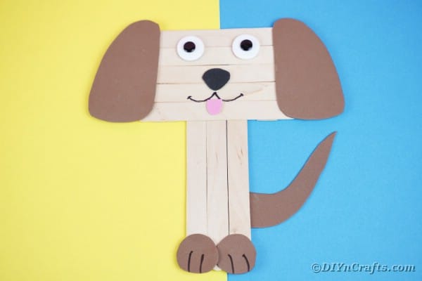 Craft stick puppy on blue and yellow paper
