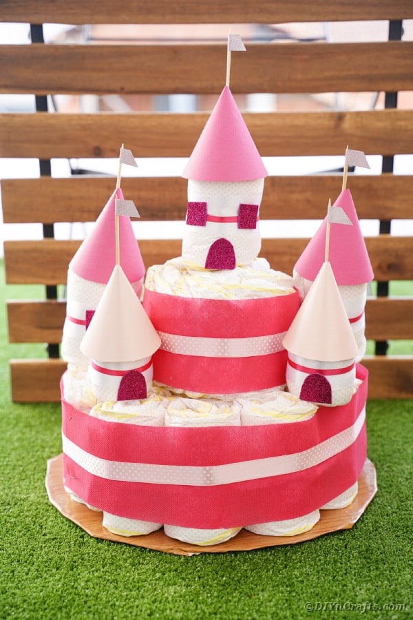 Diaper castle cake in front of wooden slats