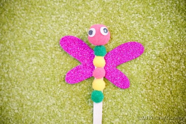 Craft stick dragonfly laying on grass