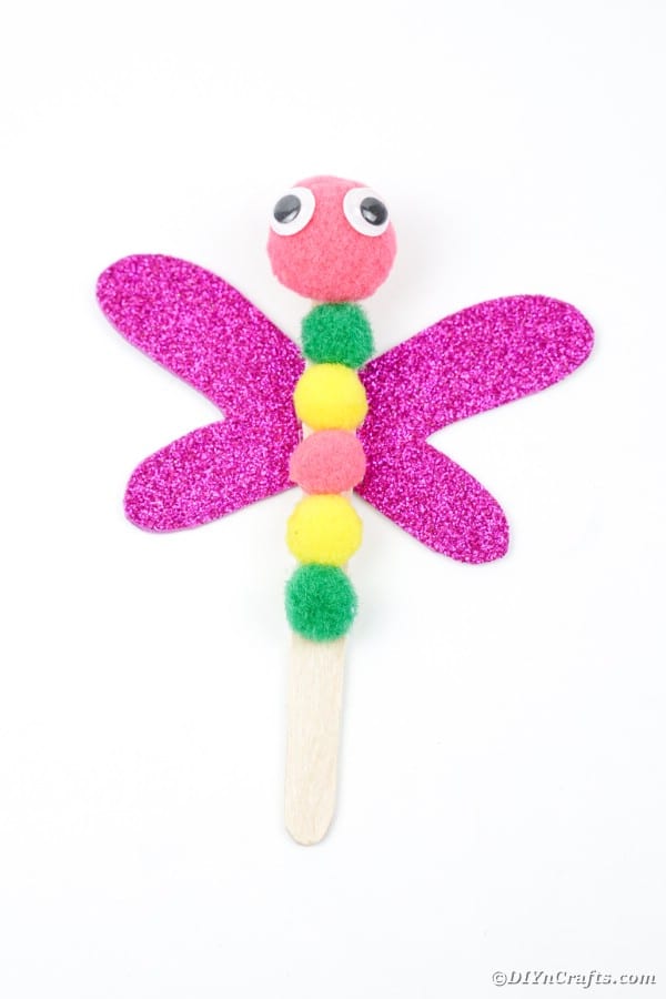 Craft stick dragonfly laying on white table