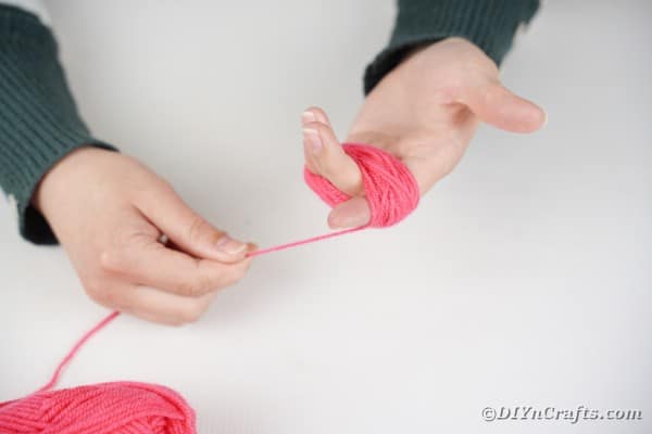 Wrapping pink yarn around palm of hand