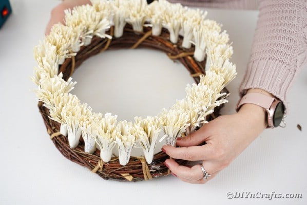 Gluing frigned paper flowers to grapevine wreath