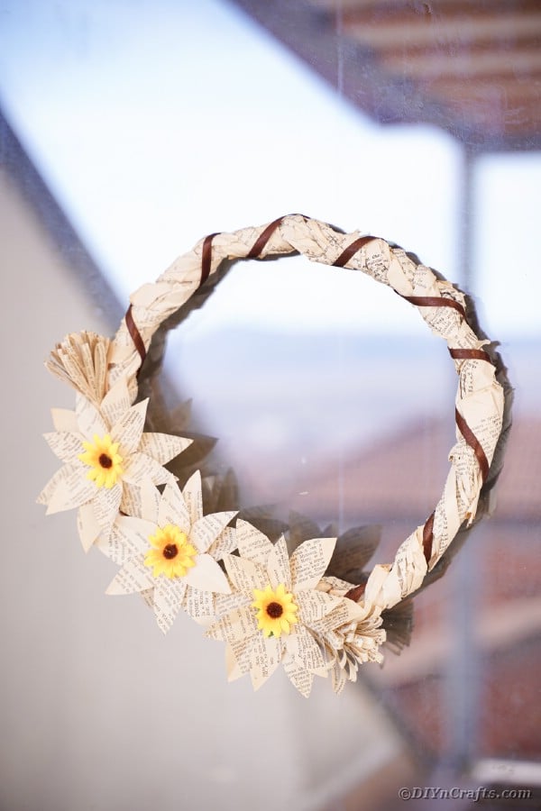 Book page grapevine wreath hanging on window