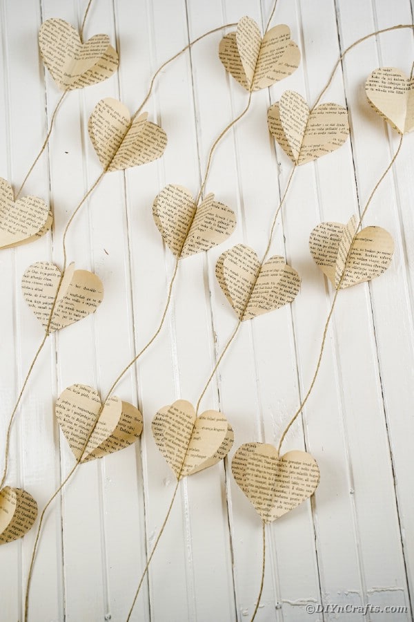 Old book page paper heart garland on white wood