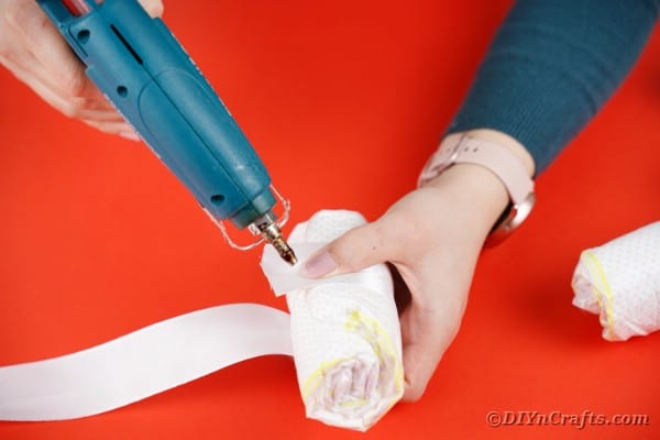 Adding white ribbon to diaper