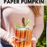 Woman in pink sweater holding paper pumpkin