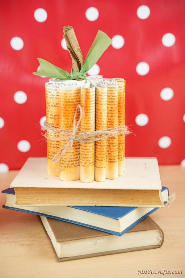 Book page pumpkin on stack of books by polka dot background