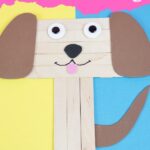 Craft stick puppy on blue and yellow paper
