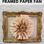 Framed paper fan flower on brick wall