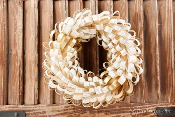 Book page wreath hanging against wooden slats