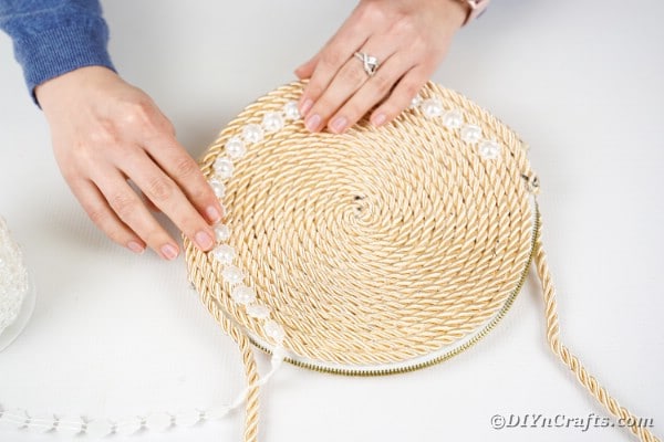 Gluing beads around the outside of the purse