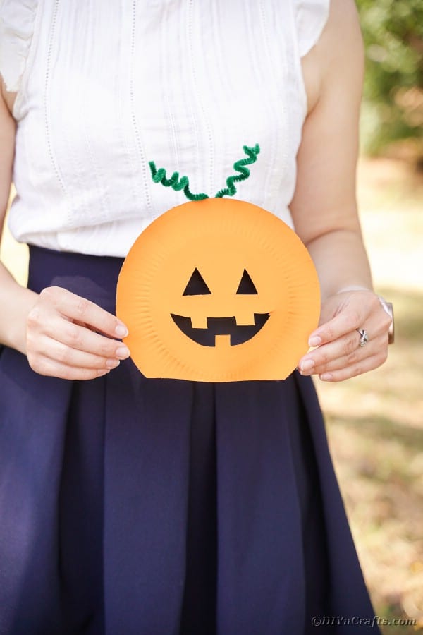 Woman holding paper plate pumpkin