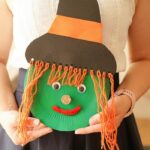 Woman holding paper plate witch face
