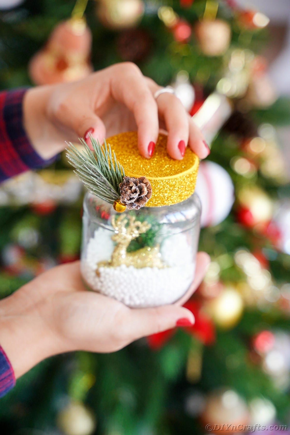 Woman holding snow globe in front of christmas tree