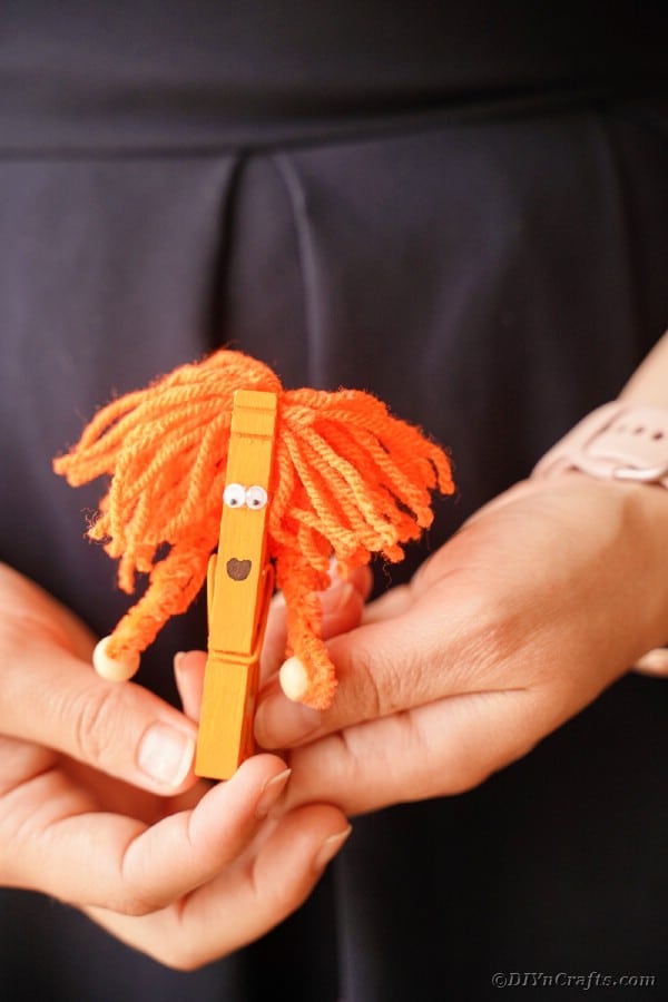 Woman holding orange clothespin monster