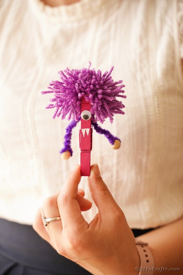 Woman holding purple clothespin monster