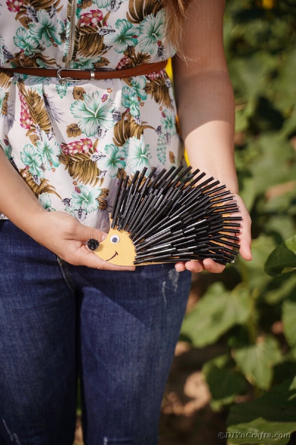 Woman holding hedgehog with black straws