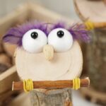 Wooden owl with purple feathers on table