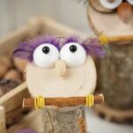 Wooden owl with purple feathers on table