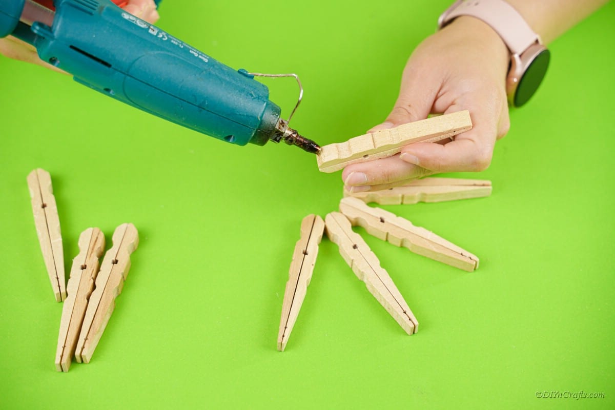 hot glue gun applying glue to wooden clothespins in hand 