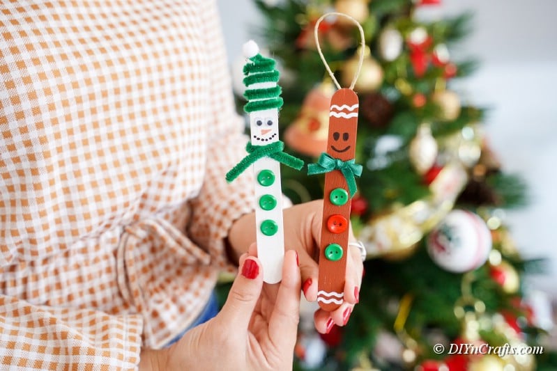 popsicle stick craft being helkd by woman in front of christmas tree