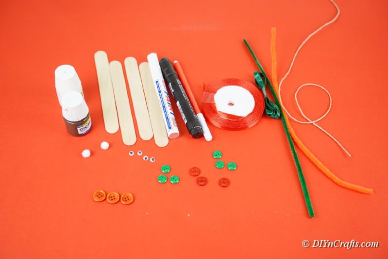 craft supplies on a table including popsicle sticks pipecleaner paint