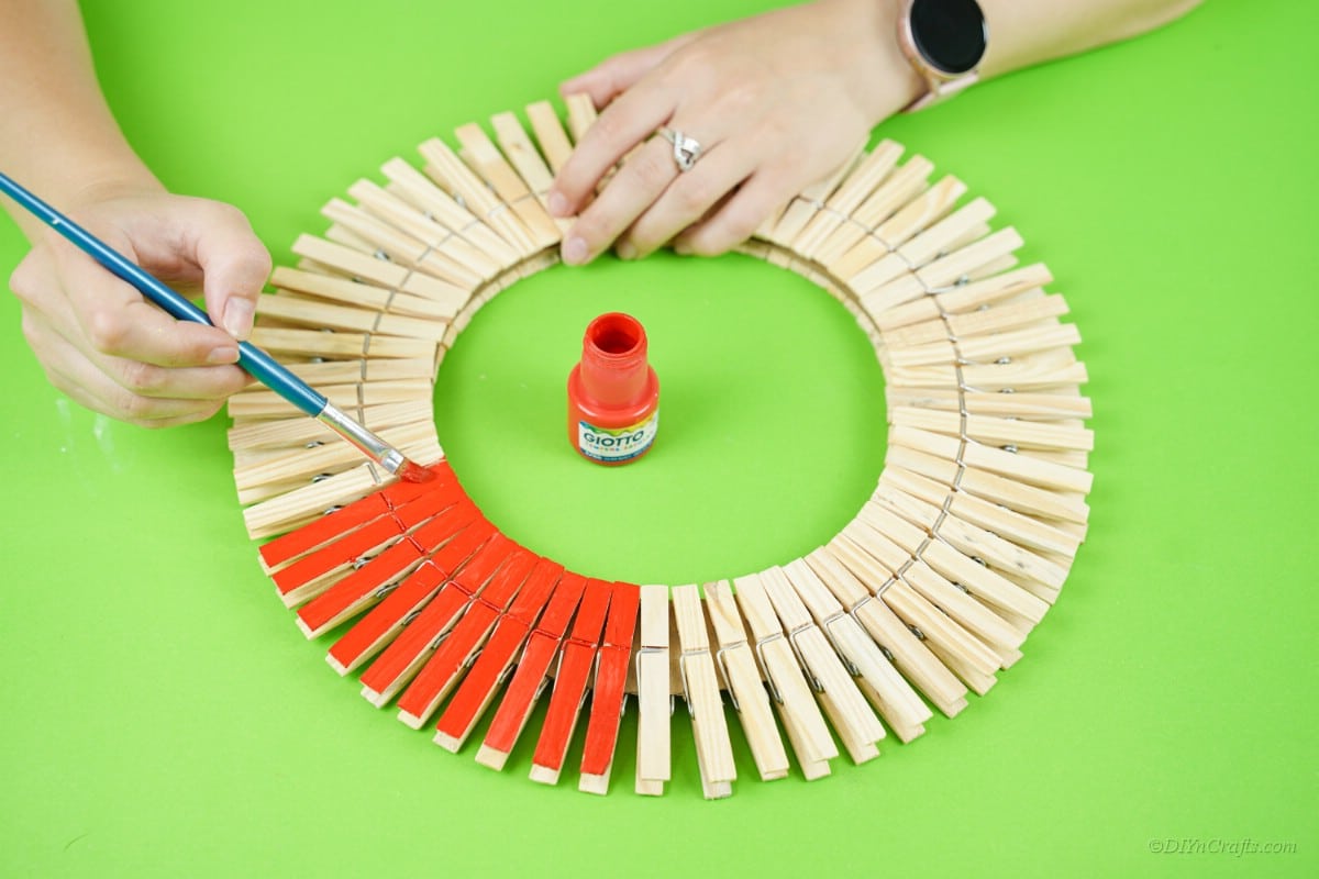 painitng red paint onto wood clothespins