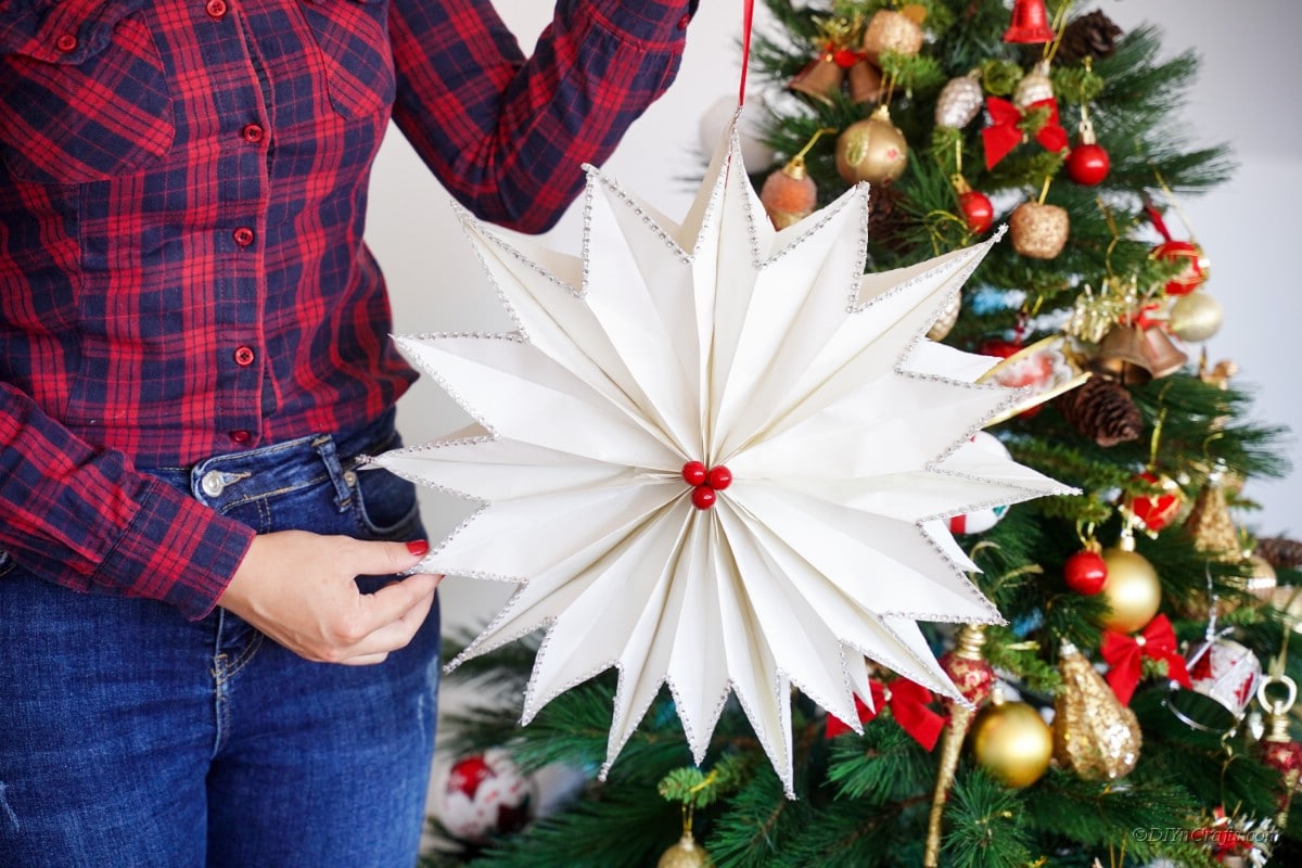 Giant star made from white paper being held by person