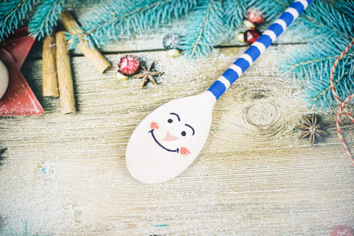 Snowman character painted craft wood spoon on table 