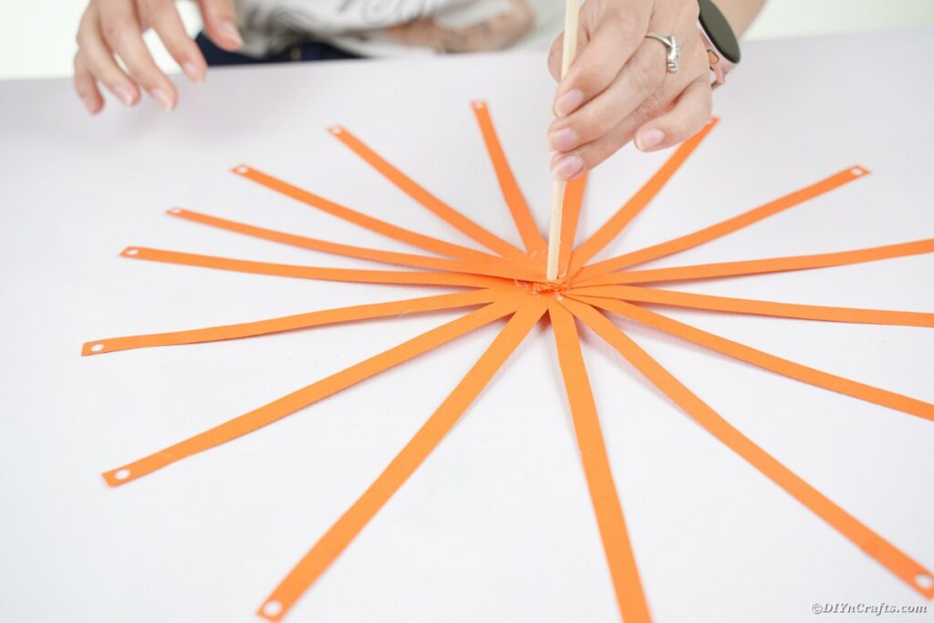 Orange paper strips around dowel