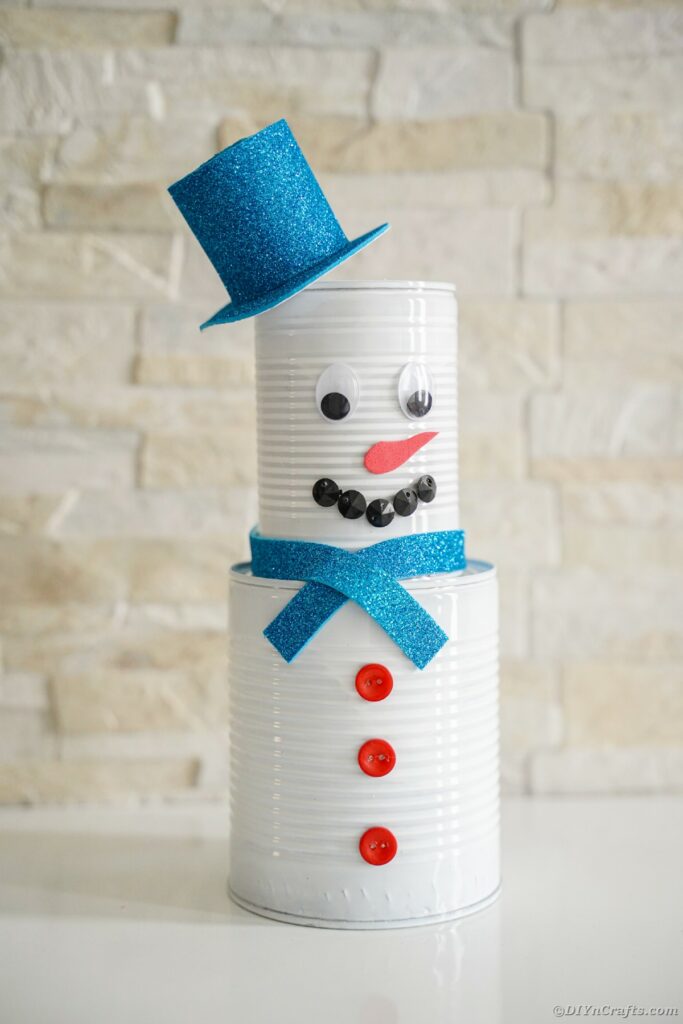 Tin can snowman against brick wall