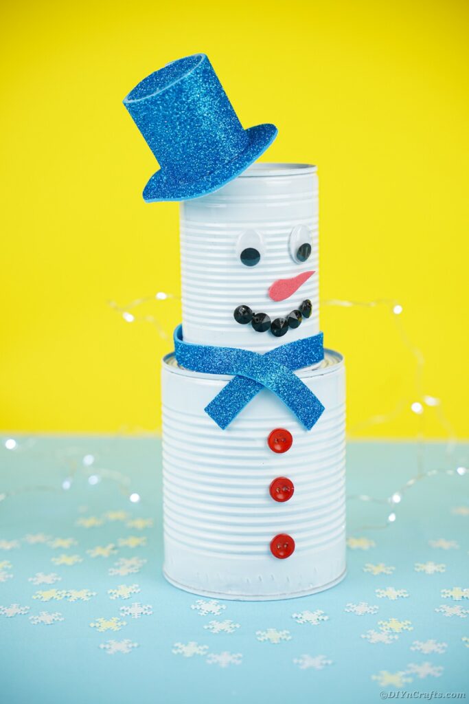 Tin can snowman against yellow background